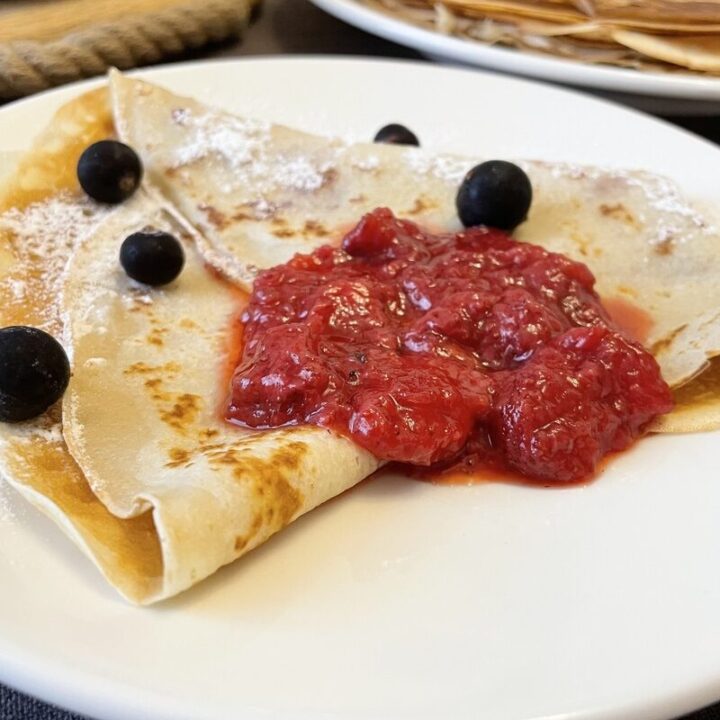 Beautifully served pancake with strawberry jam and berries.