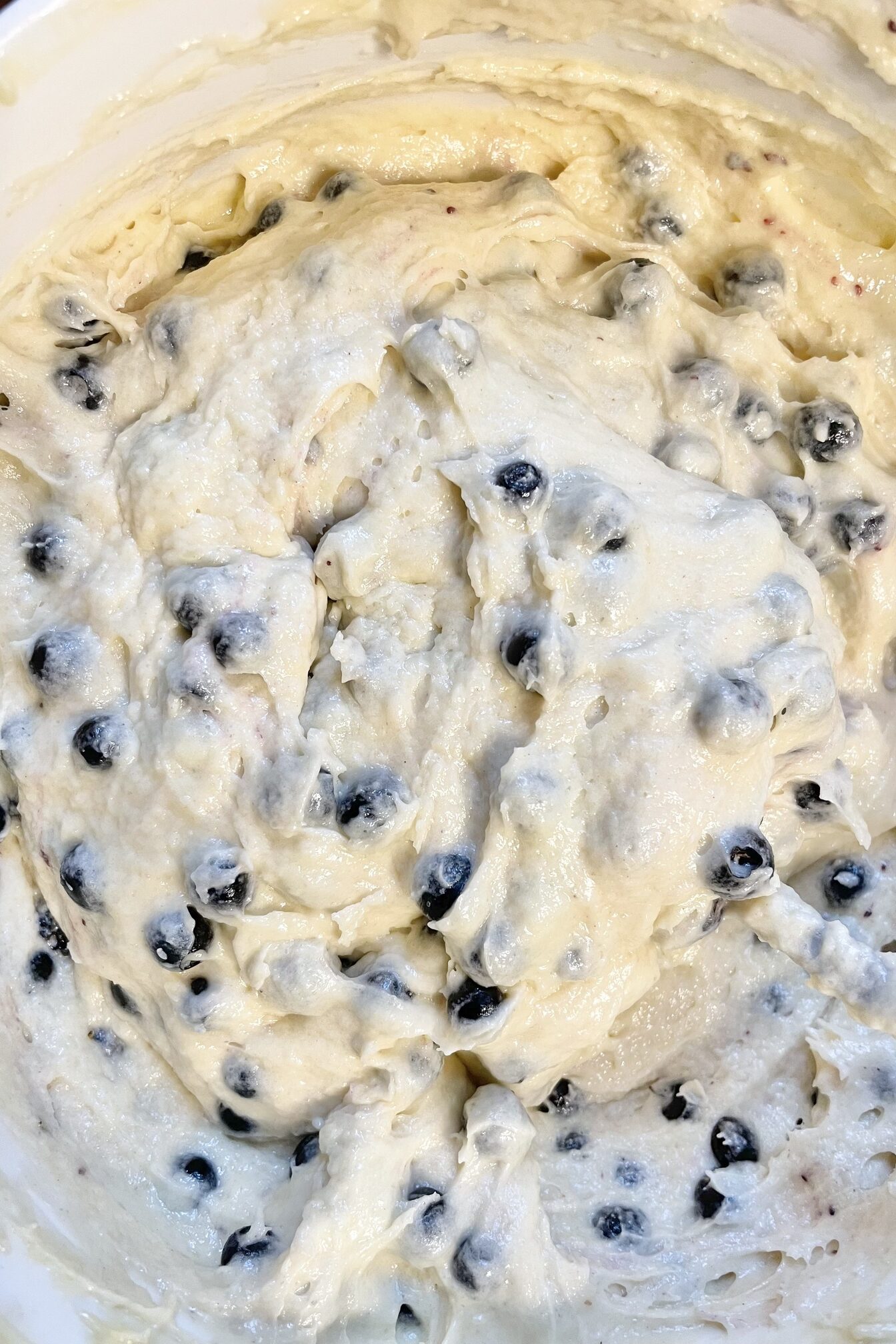 Blueberry muffin dough in a white bowl.