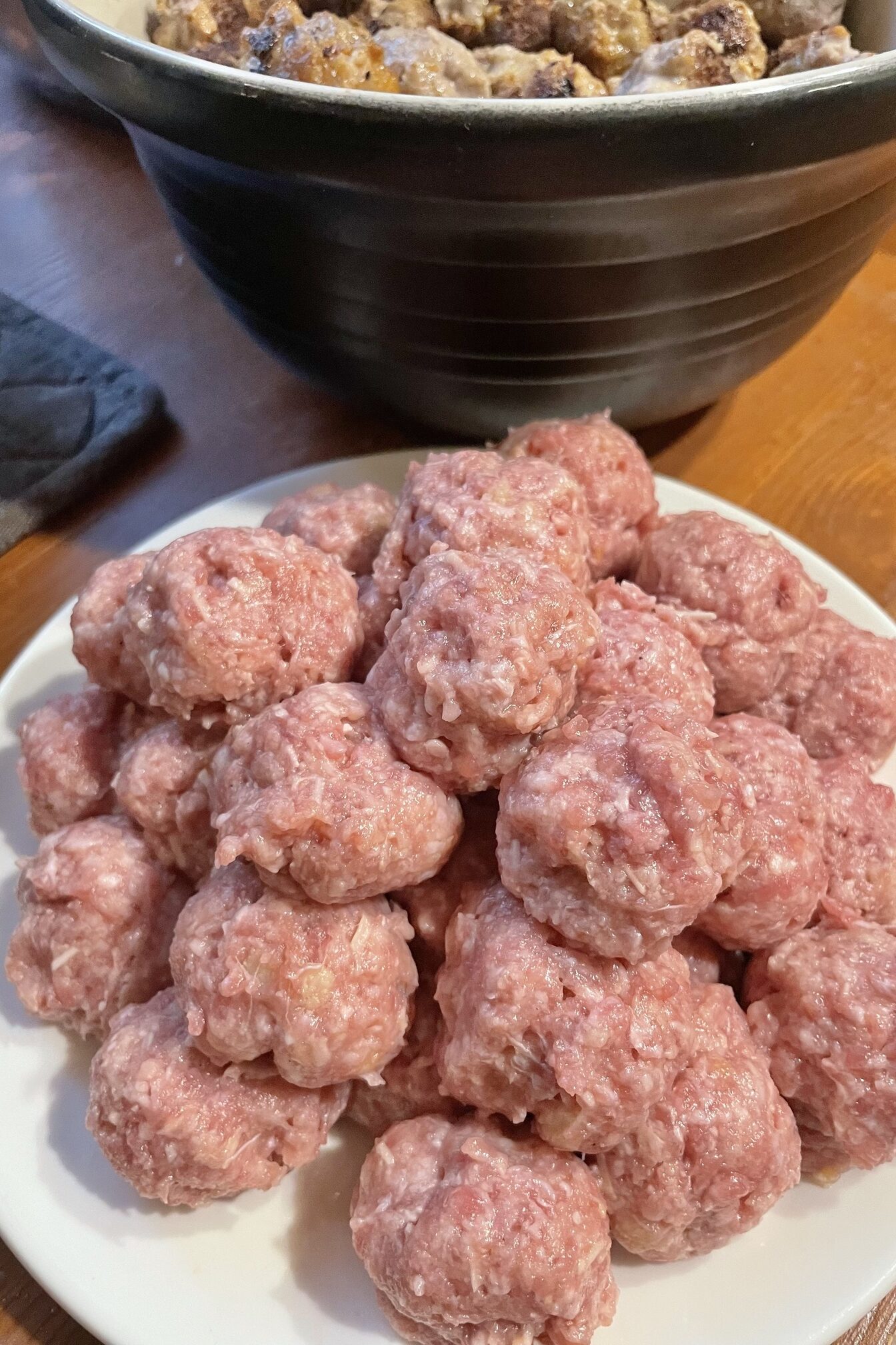 Raw meatballs on a white plate.