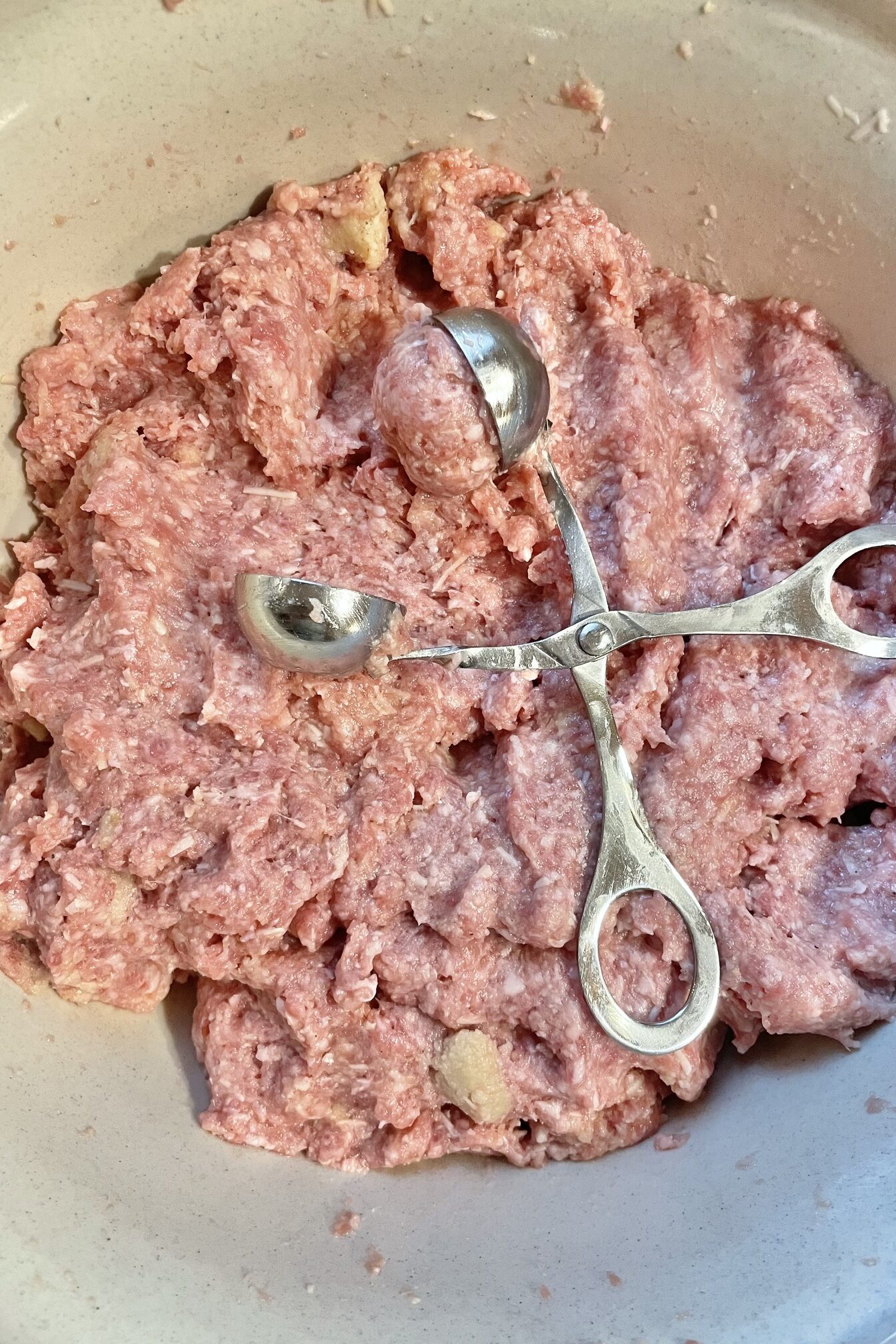 Meat mixture and meatball tongs.